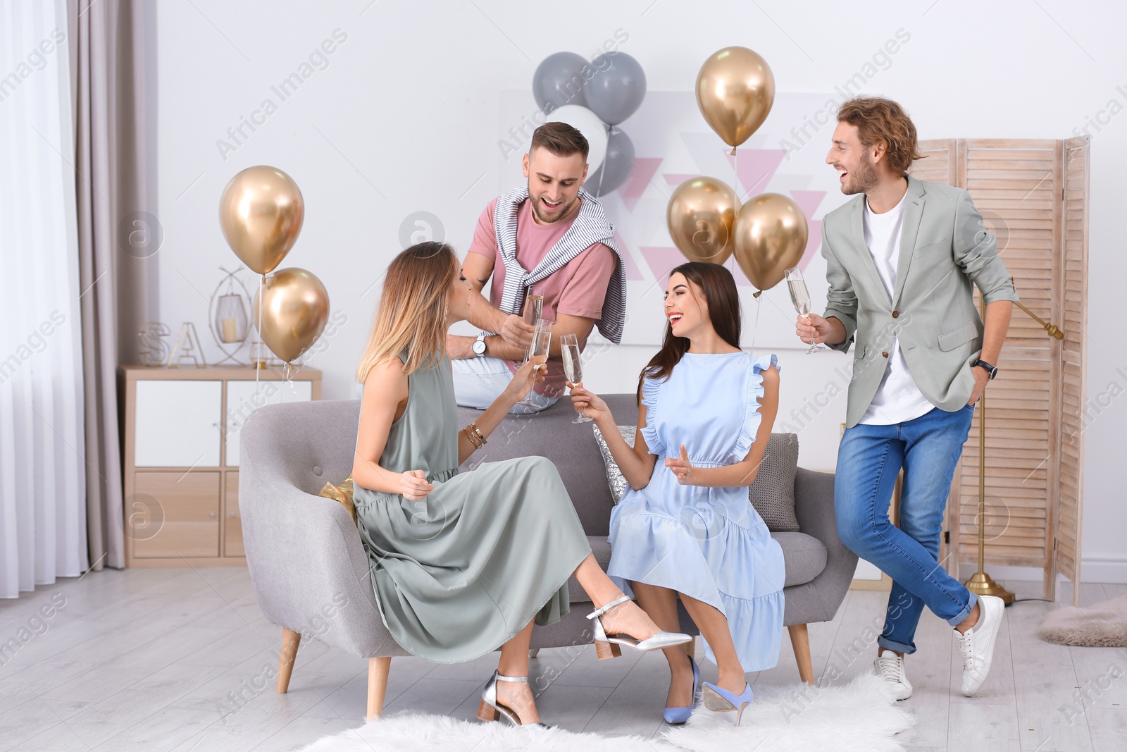 Photo of Happy friends with champagne in glasses at home