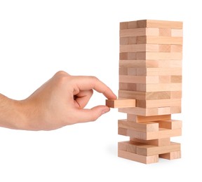 Playing Jenga. Man removing wooden block from tower on white background, closeup