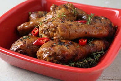 Photo of Chicken legs glazed in soy sauce with black sesame, chili pepper and thyme on light table, closeup