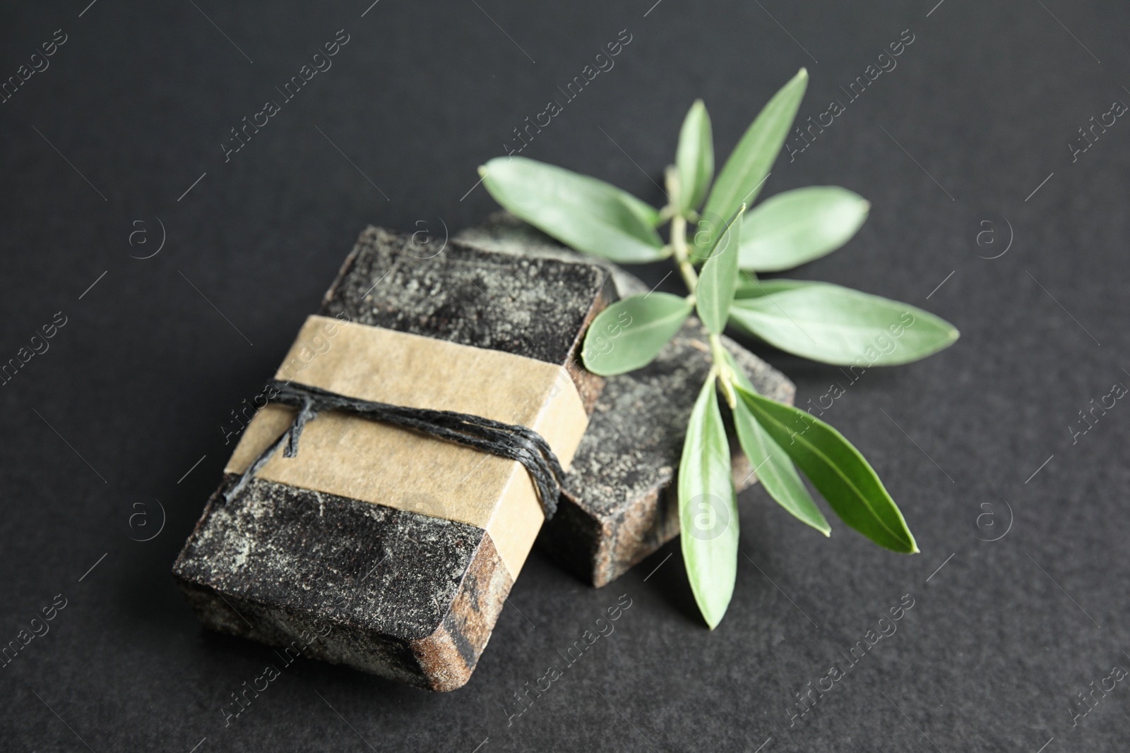 Photo of Handmade soap bars and olive twig on black background