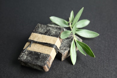 Handmade soap bars and olive twig on black background