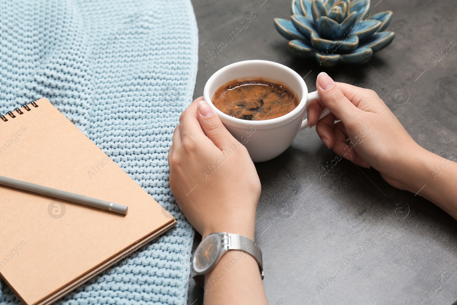 Photo of Young woman with cup of delicious coffee at table