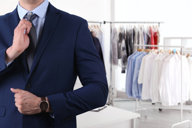 Businessman and blurred view of dry-cleaner's interior, closeup. Space for text 