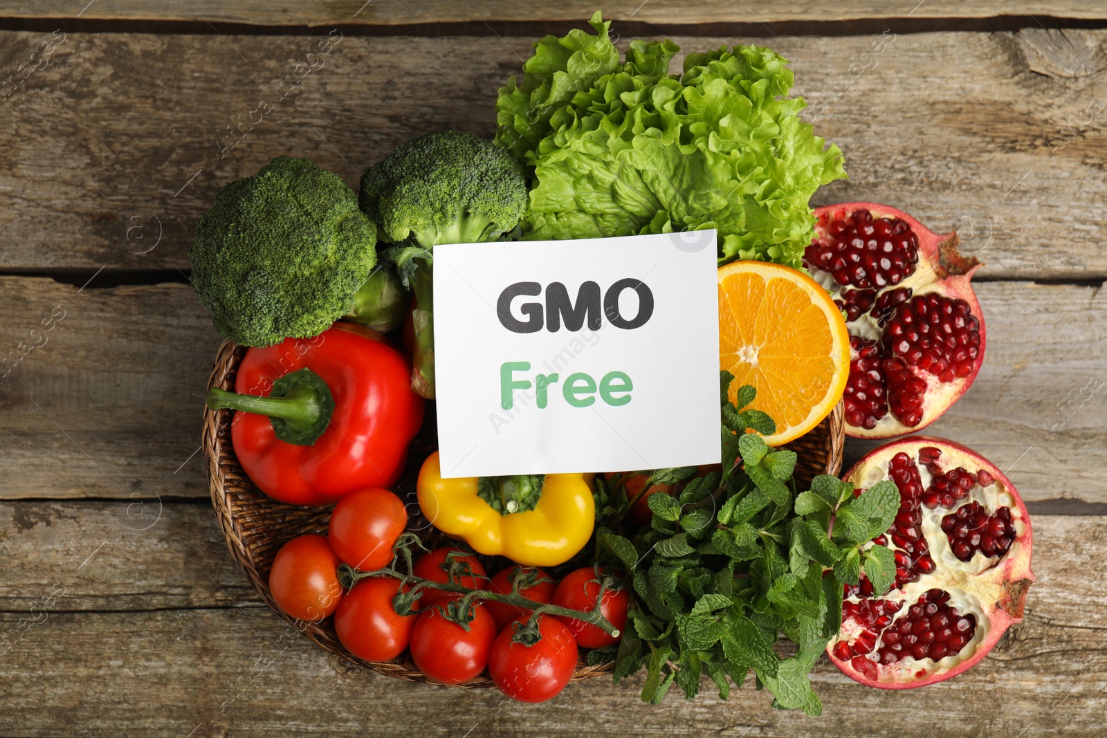 Photo of Tasty fresh GMO free products and paper card on wooden table, flat lay