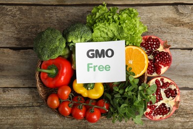 Photo of Tasty fresh GMO free products and paper card on wooden table, flat lay