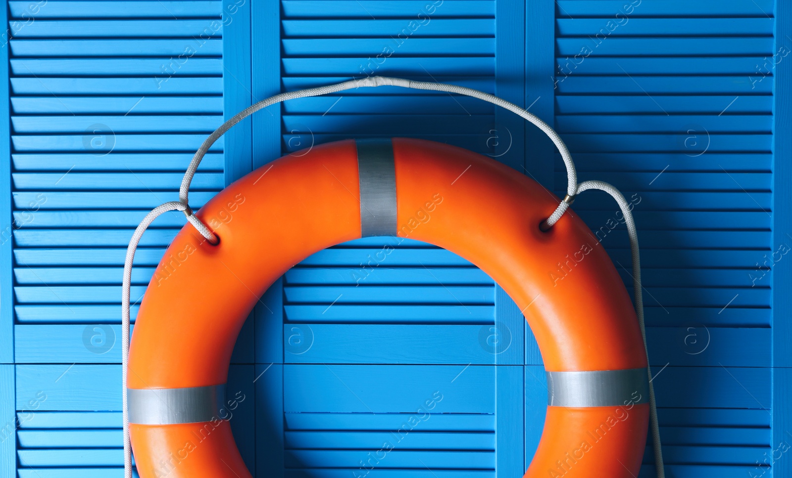 Photo of Orange lifebuoy on blue wooden background. Rescue equipment