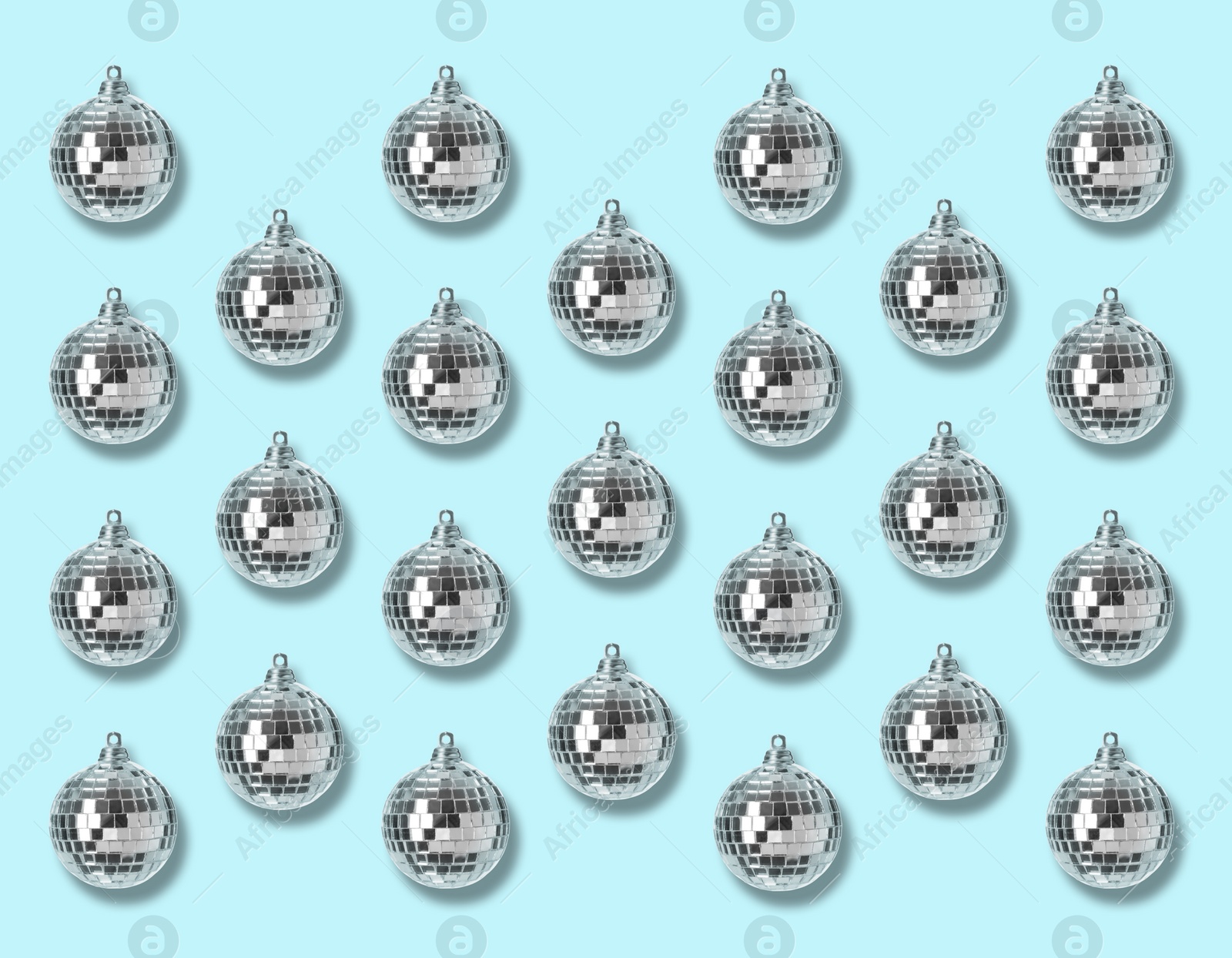 Image of Many shiny disco balls on light blue background, flat lay