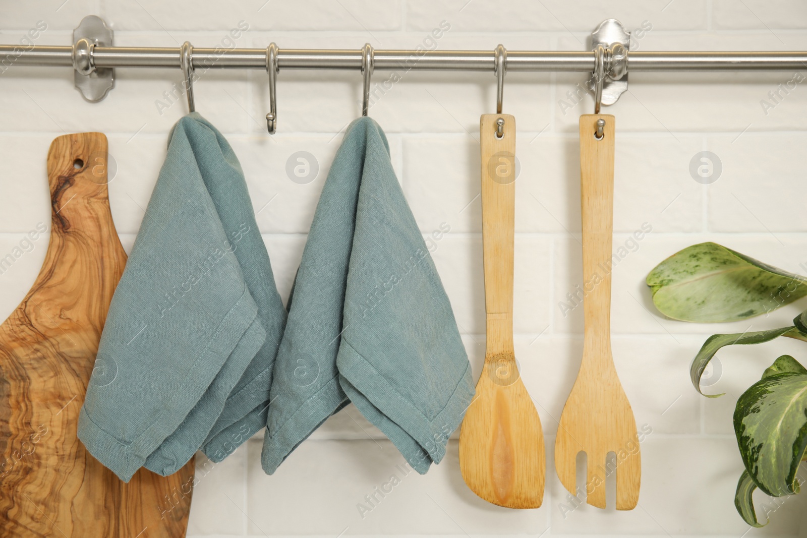 Photo of Clean towels and utensils hanging on rack in kitchen