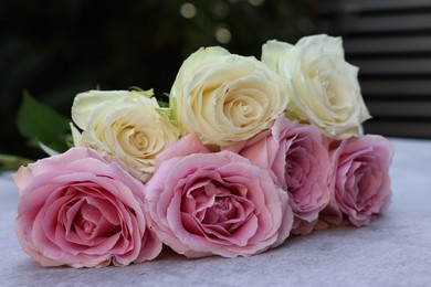 Photo of Beautiful bouquet of roses on light grey table outdoors, closeup