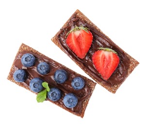 Fresh crunchy rye crispbreads with chocolate spread and sweet berries isolated on white, top view