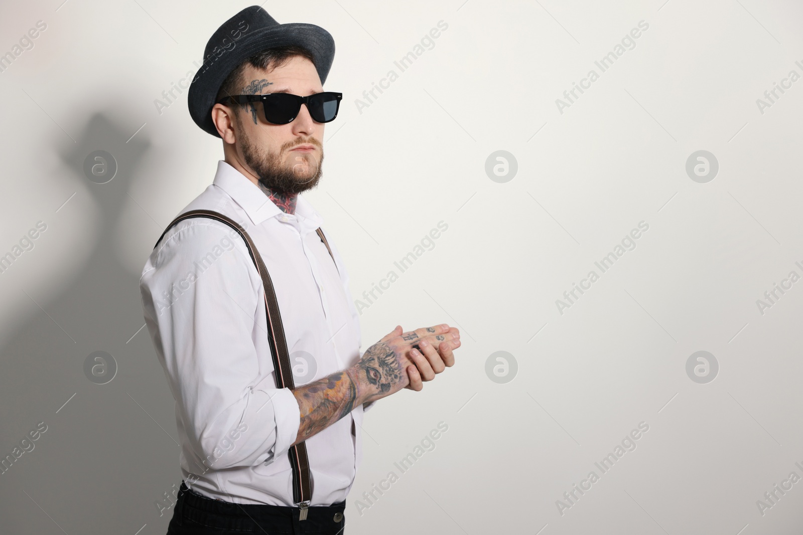 Photo of Handsome hipster man wearing stylish sunglasses on light grey background. Space for text