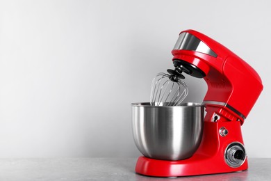 Photo of Modern red stand mixer on light gray table, space for text
