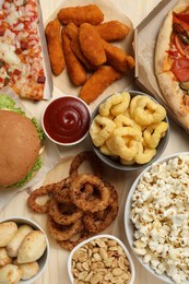 Pizza, chicken nuggets and other fast food on wooden table, flat lay