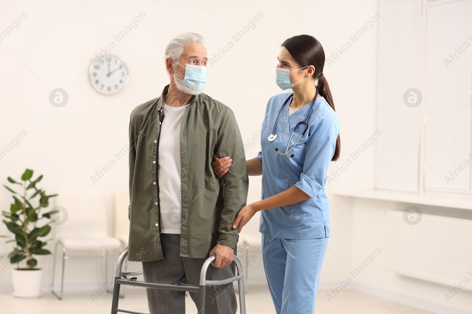 Photo of Young nurse supporting elderly patient in hospital