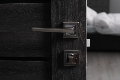 Open wooden door with metal handle, closeup