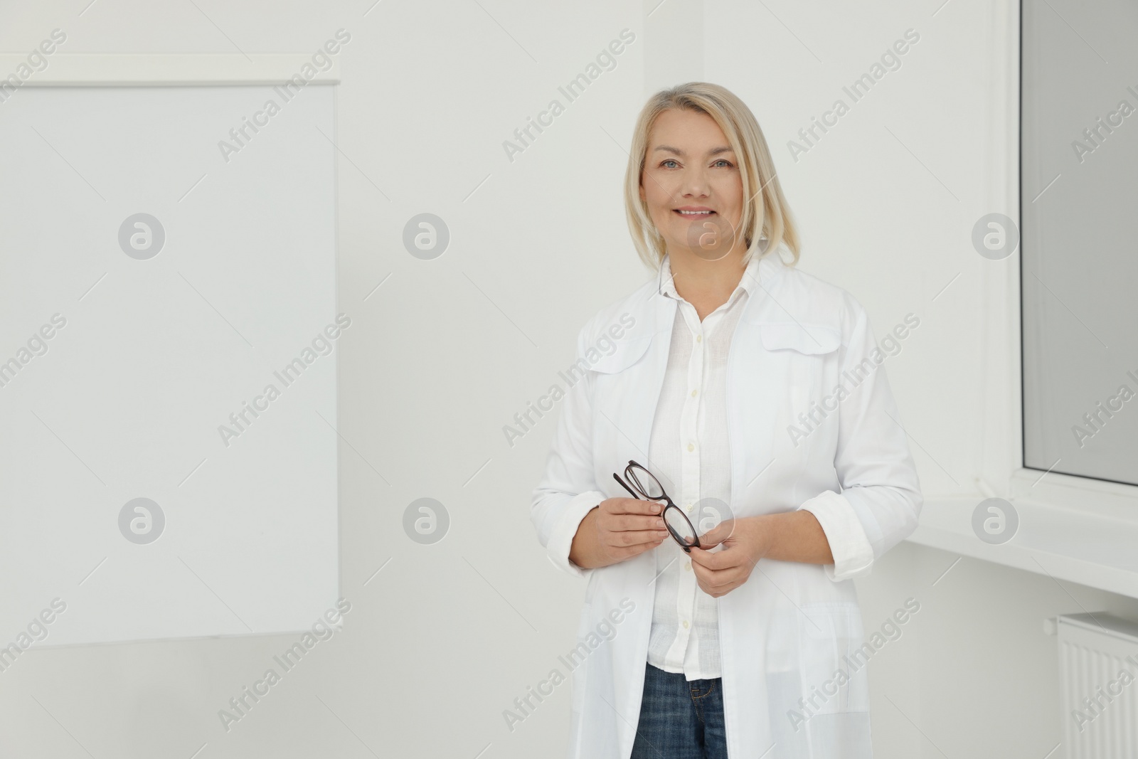 Photo of Professional doctor wearing medical coat near flipchart board in clinic