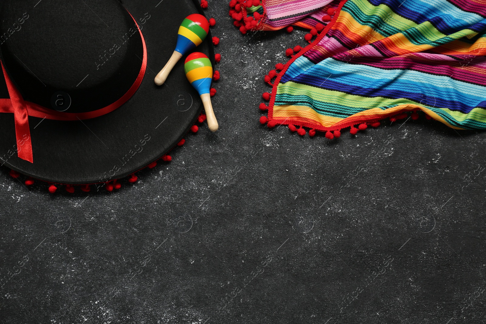 Photo of Mexican sombrero hat, maracas and colorful poncho on grey textured background, flat lay. Space for text