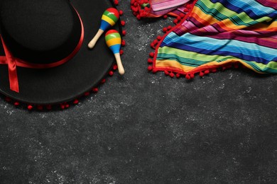 Mexican sombrero hat, maracas and colorful poncho on grey textured background, flat lay. Space for text