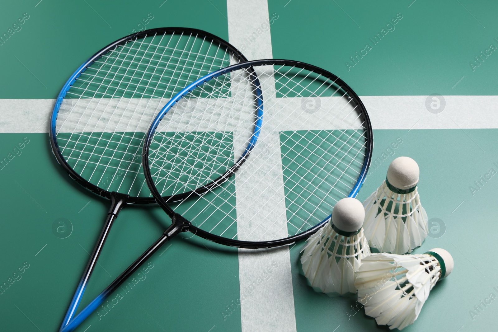 Photo of Feather badminton shuttlecocks and rackets on green table, closeup