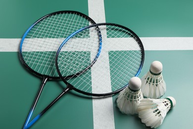 Feather badminton shuttlecocks and rackets on green table, closeup