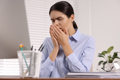 Photo of Woman coughing at table in office. Cold symptoms