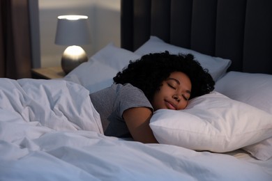 Photo of Young woman sleeping in soft bed at night