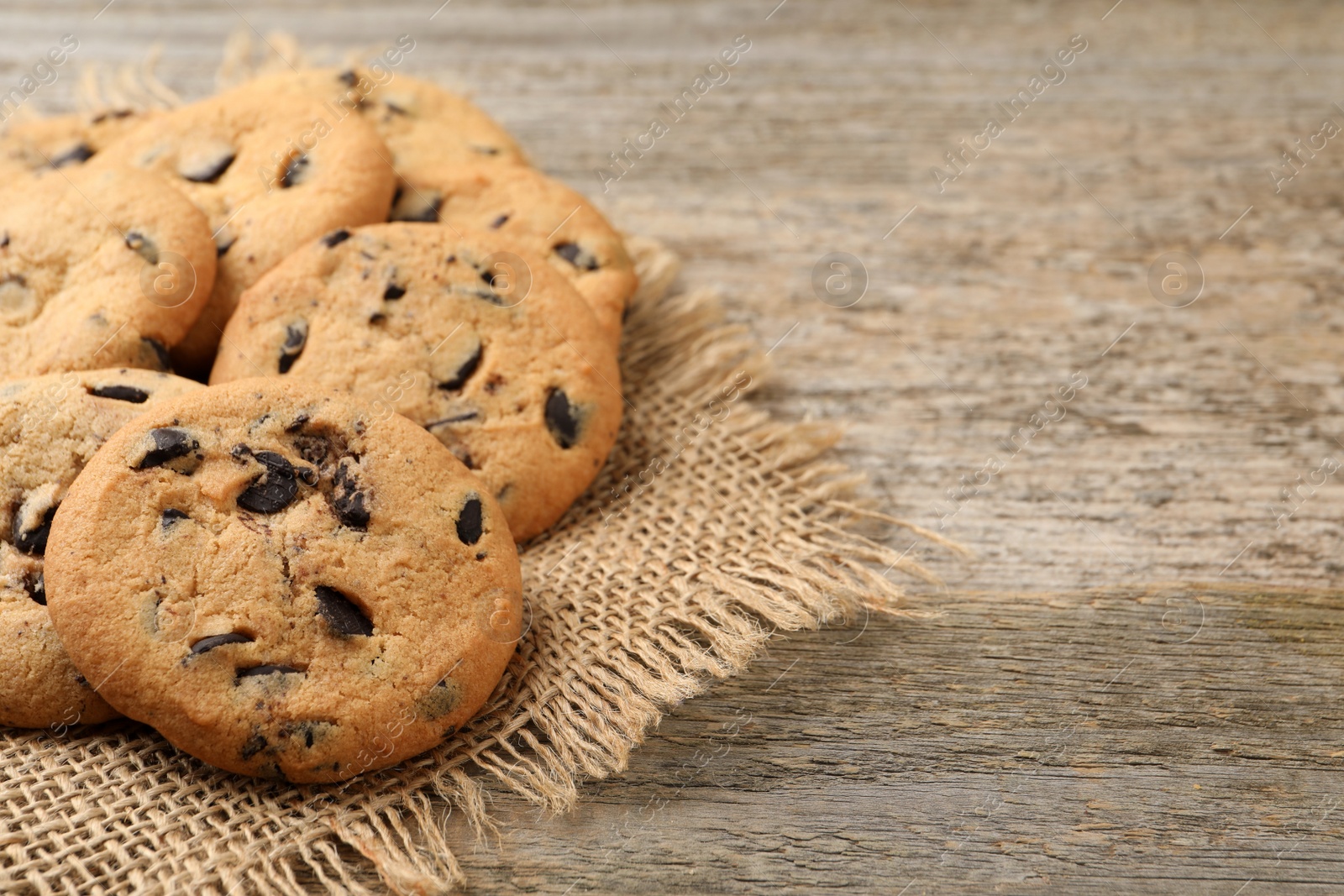 Photo of Delicious chocolate chip cookies on wooden table. Space for text