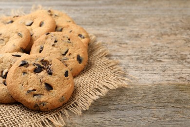 Photo of Delicious chocolate chip cookies on wooden table. Space for text