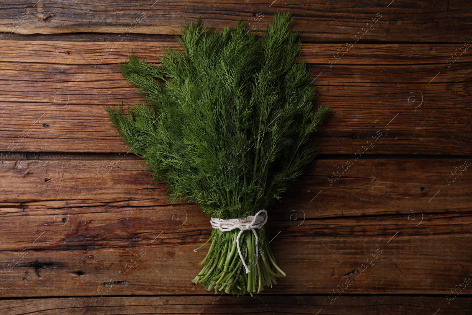 Photo of Bunch of fresh green dill on wooden table, top view