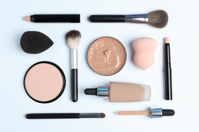 Flat lay composition with skin foundation, powder and beauty accessories on white background