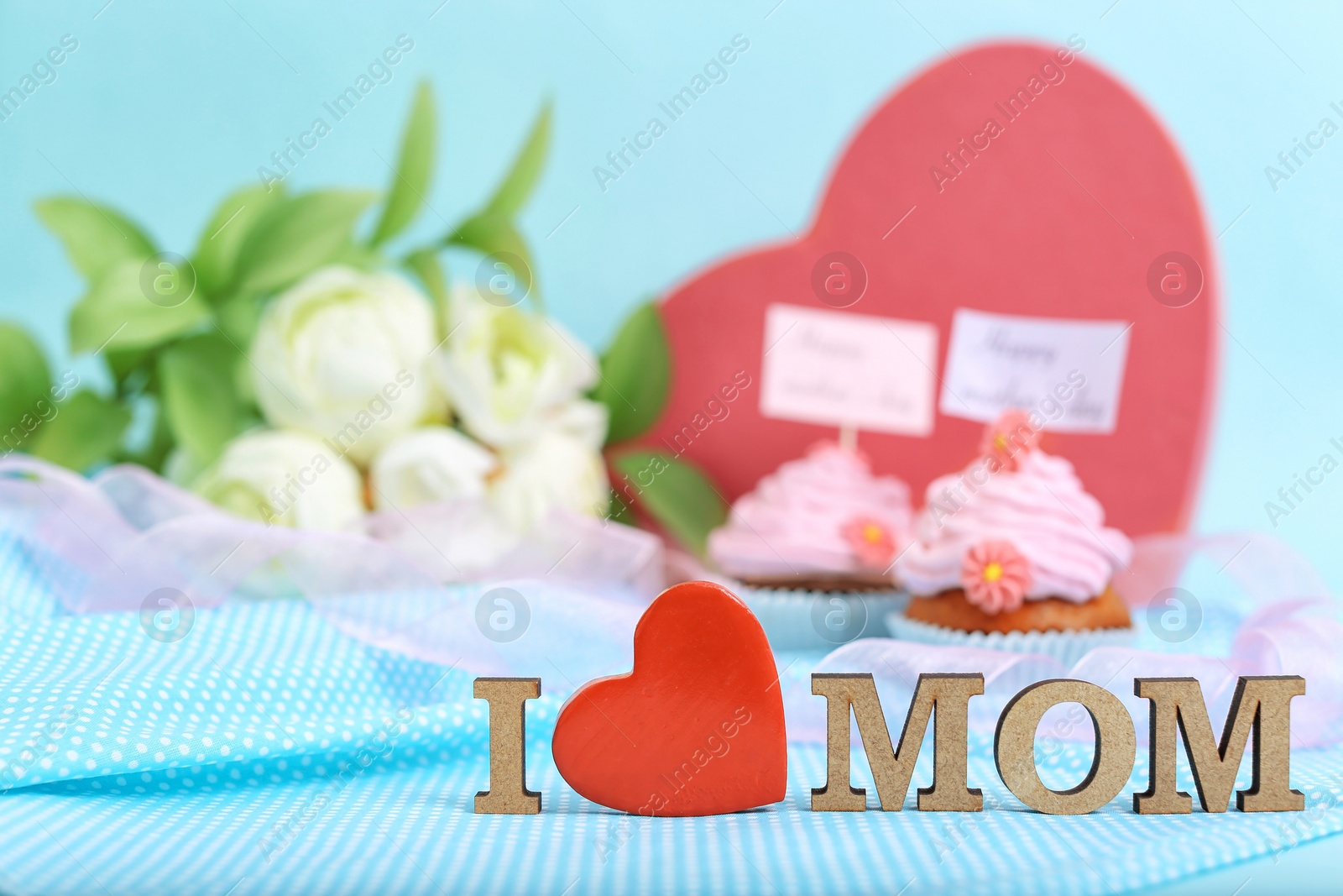 Photo of Beautiful composition with phrase I LOVE MOM, flowers, gift and cupcakes for Mother's Day on color background