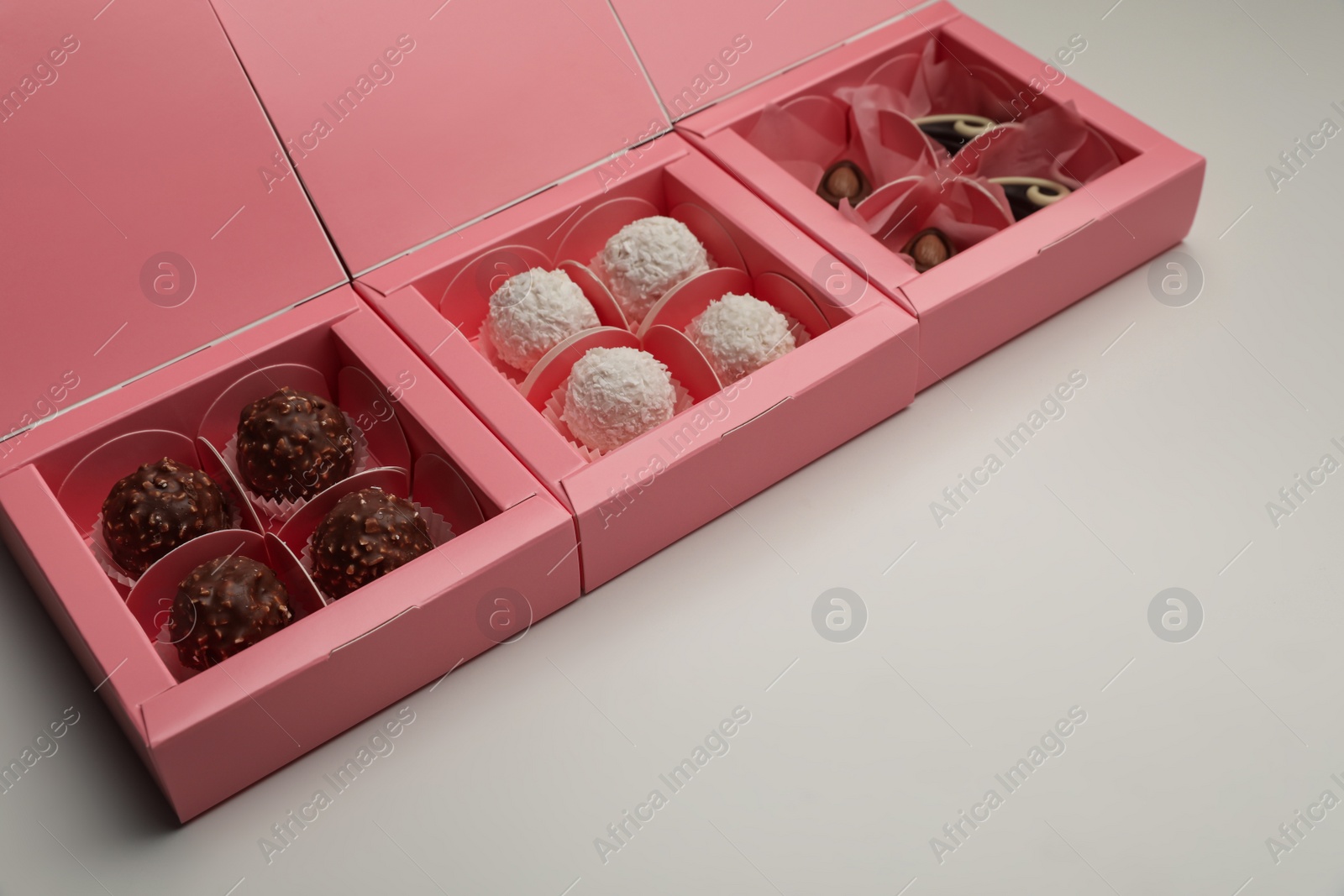 Photo of Delicious candies in pink boxes on light grey background. Production line