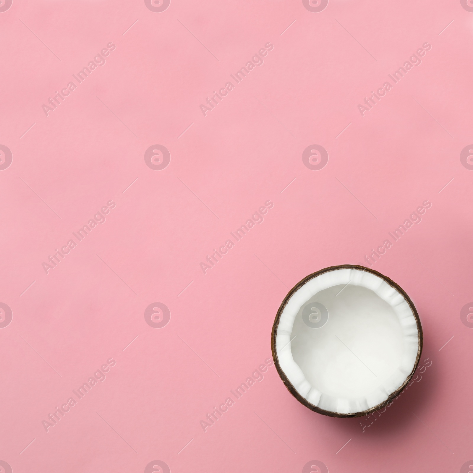 Photo of Fresh coconut half on pink background, top view. Space for text