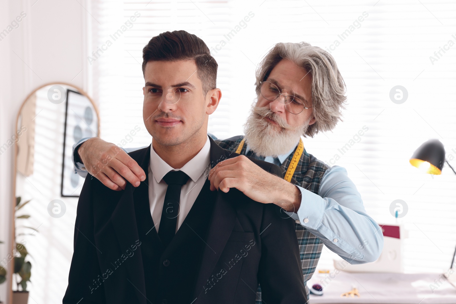 Photo of Professional tailor working with client in atelier