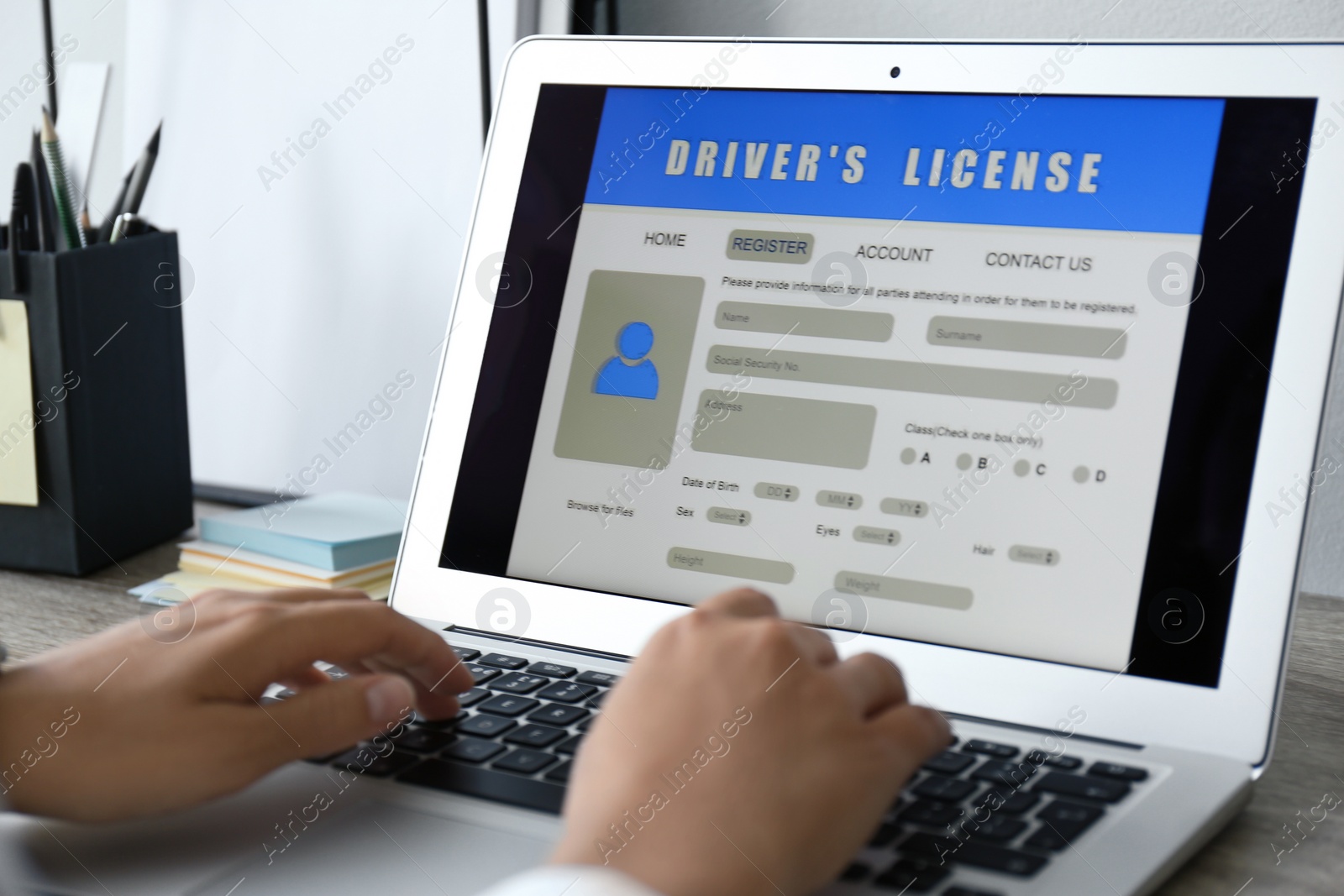 Photo of Woman using laptop to fill driver's license application form at table in office, closeup