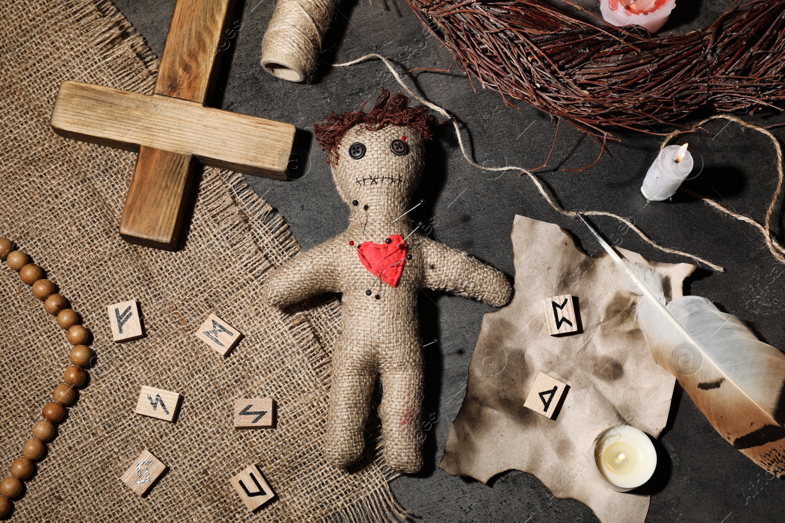 Photo of Voodoo doll pierced with pins and ceremonial items on grey table, flat lay