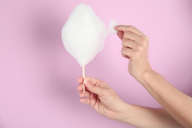 Photo of Woman eating yummy cotton candy on color background, closeup