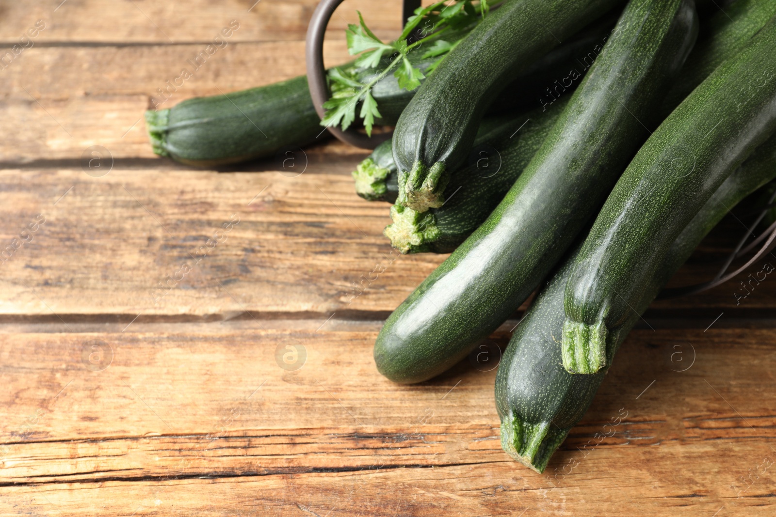 Photo of Green zucchinis on wooden table, closeup. Space for text