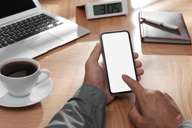 Photo of Man holding mobile phone with empty screen at table, closeup