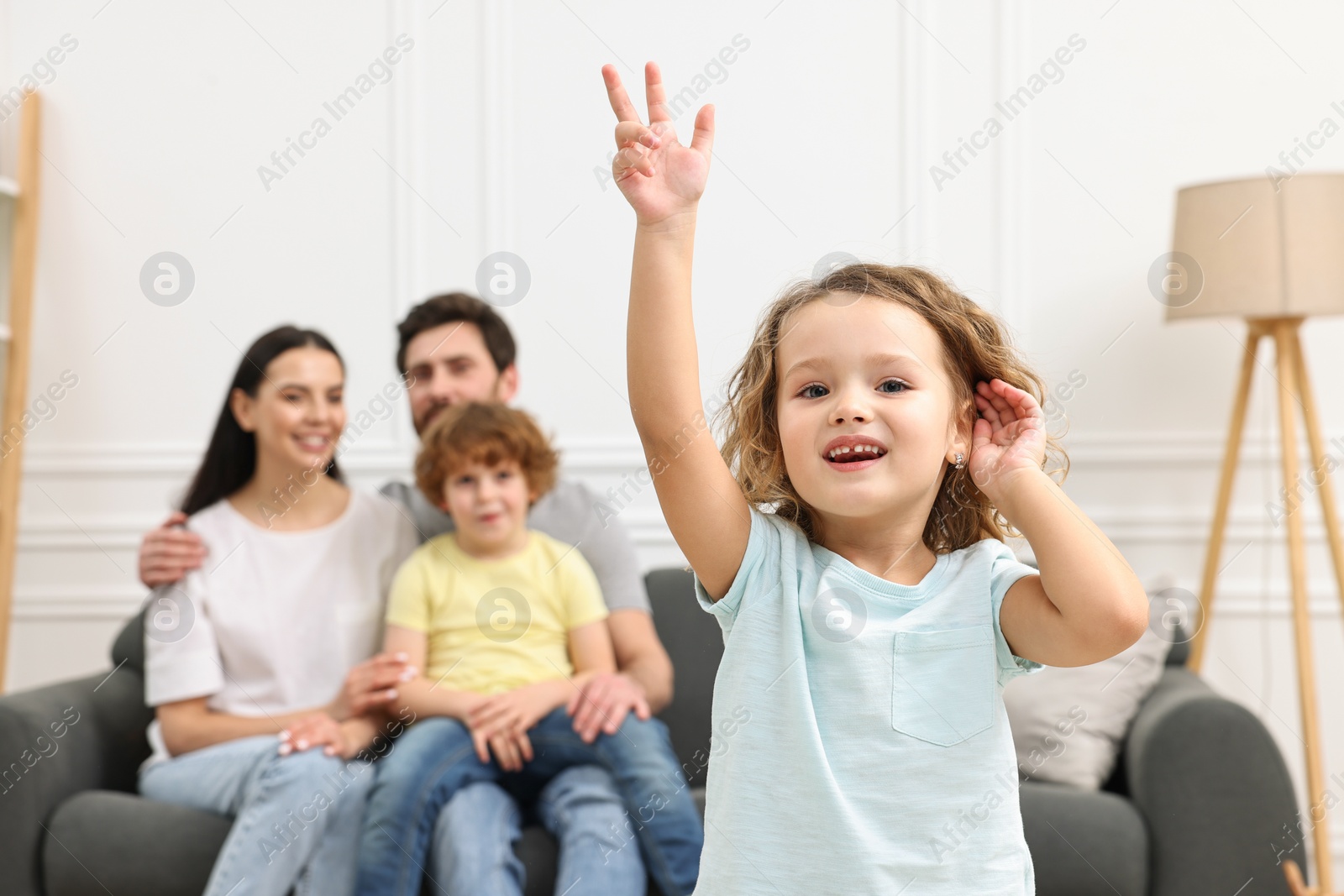 Photo of Happy family having fun at home. Daughter dancing while her relatives resting on sofa