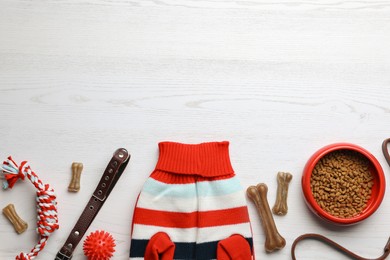 Photo of Flat lay composition with dog clothes, food and accessories on white wooden table. Space for text