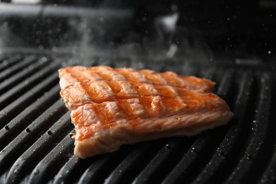 Tasty salmon cooking on electric grill, closeup