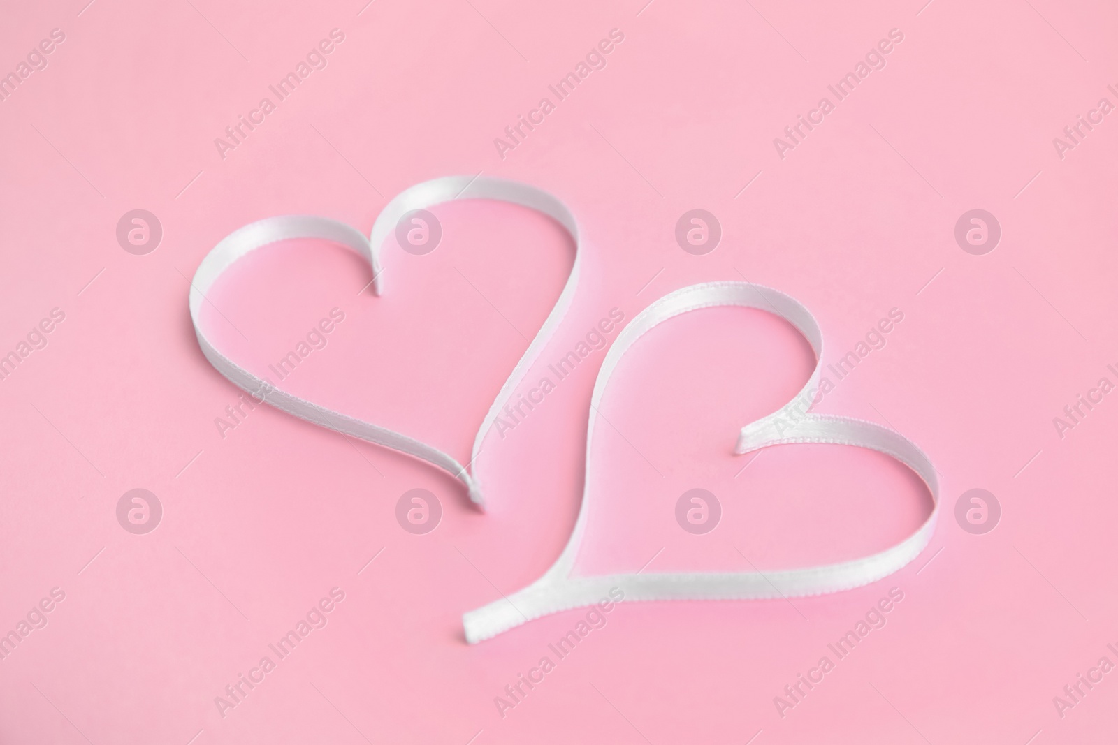 Photo of Hearts made of white ribbon on pink background. Valentine's day celebration