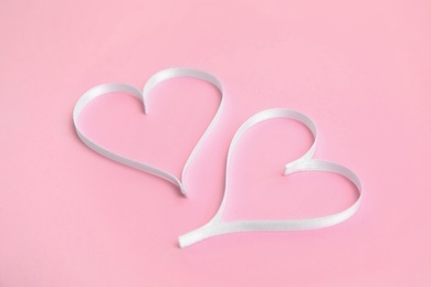 Photo of Hearts made of white ribbon on pink background. Valentine's day celebration