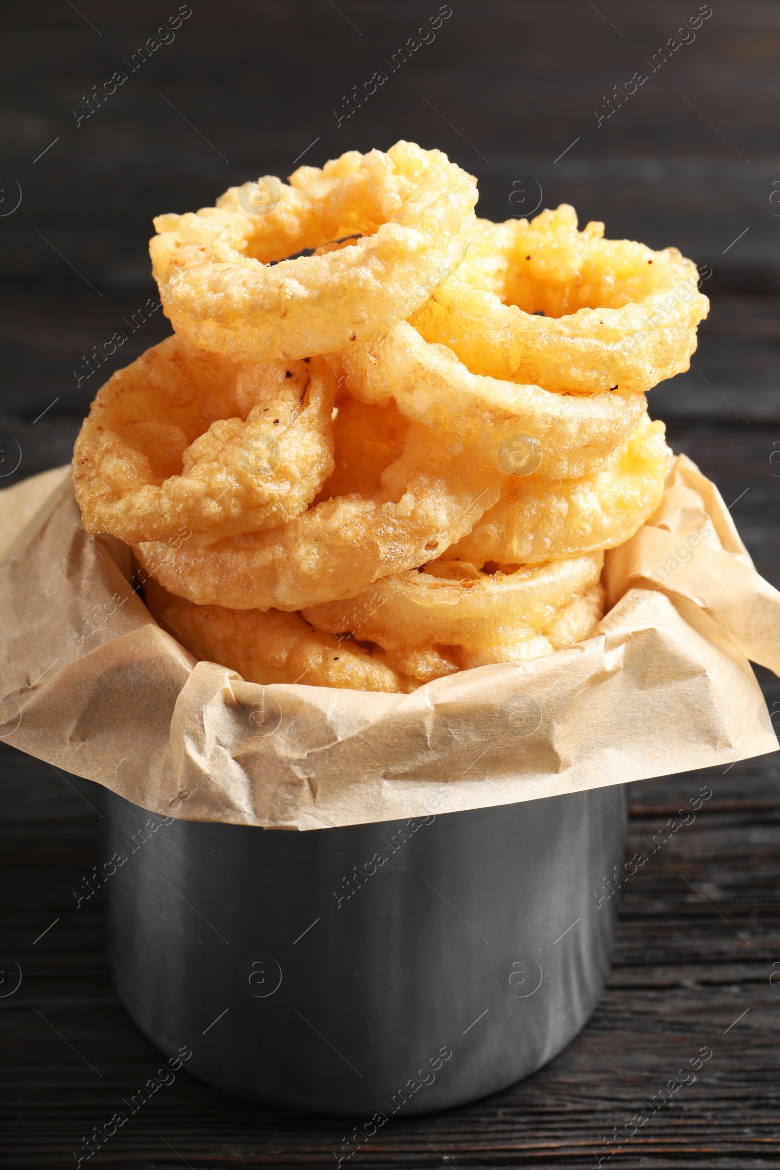 Photo of Dishware with homemade crunchy fried onion rings on wooden table, closeup