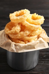 Dishware with homemade crunchy fried onion rings on wooden table, closeup