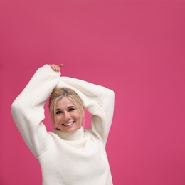 Photo of Happy woman in stylish sweater on pink background. Space for text
