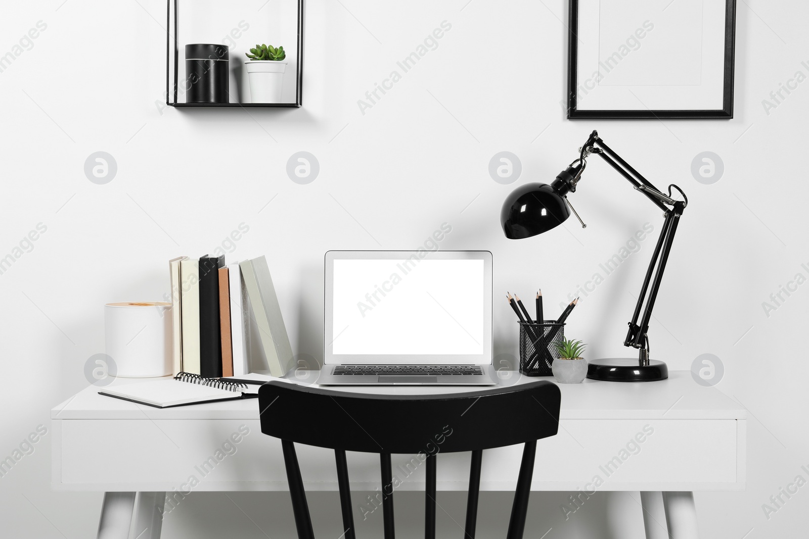 Photo of Cozy workspace with computer, lamp and stationery on wooden desk at home