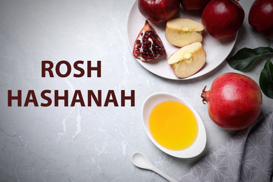 Honey, apples and pomegranate on marble table, flat lay. Rosh Hashanah holiday