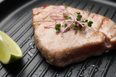 Delicious tuna steak with lime and microgreens in grill pan, closeup